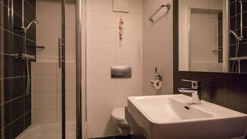 A modern bathroom with a glass shower enclosure, a white sink, and a toilet.