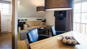 Una sala moderna con un sofá, una mesa de comedor con una bandeja de bocadillos y un televisor montado en la pared.