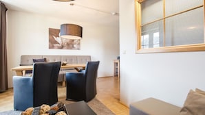 Una sala de estar moderna con un sofá, una mesa de centro con un control remoto y una zona de comedor con una mesa y sillas.