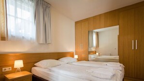Une chambre d’hôtel avec un grand lit, une table de chevet, une armoire et un miroir.