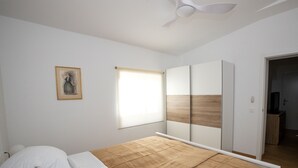 A bedroom with a bed, a ceiling fan, a window with blinds, a wardrobe, and a framed picture on the wall. - La Casita mit Pool (Valle del Sol)