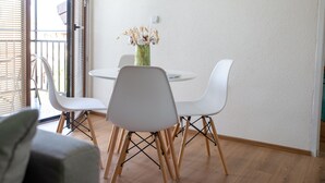 A dining area with a round table, white chairs, and a vase with flowers. - Daria Apartment (Ohrid)