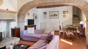 A living room with a sofa, TV, fireplace, dining area, and staircase. - Stunning  villa with WIFI, private pool, A/C, hot tub, TV, patio, panoramic view, close to Arezzo (Vogognano)