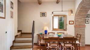 A dining area with a wooden table and chairs, a lamp, and a window with a view of greenery. - Stunning  villa with WIFI, private pool, A/C, hot tub, TV, patio, panoramic view, close to Arezzo (Vogognano)