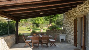 A covered outdoor patio with a stone table and chairs, a stone sink, and a view of a garden. - Stunning  villa with WIFI, private pool, A/C, hot tub, TV, patio, panoramic view, close to Arezzo (Vogognano)