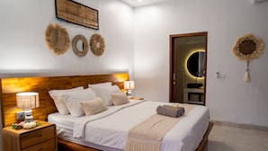 Una cama bien hecha con cabecera de madera, lámparas de noche y decoración mural.