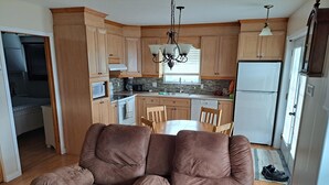 A modern kitchen with wooden cabinets, a dining table, and a built-in oven. - Very nice little condo for rent (Saguenay)