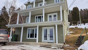 A two-story house with a porch, a garage, and a driveway. - Very nice little condo for rent (Saguenay)