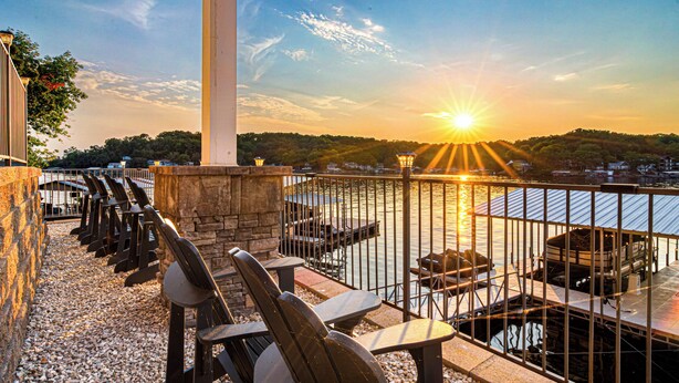 Une terrasse au bord de l’eau, avec des sièges extérieurs et une vue sur le coucher de soleil.