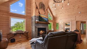 Un interior de cabaña acogedor, con chimenea, paredes de madera y un sofá de cuero.