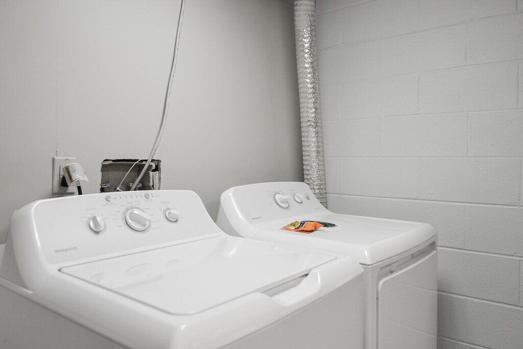 Une buanderie équipée de deux lave-linge à chargement frontal blancs et d’un sèche-linge.