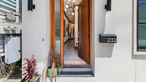 A residential entryway with a wooden door, a black mailbox, and a potted plant. - Modern Luxury Living in Unbeatable Location w/ Rooftop Deck by Lucky Savannah (Savannah)
