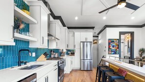 A modern kitchen with white cabinetry, stainless steel appliances, and a wooden floor. - Modern Luxury Living in Unbeatable Location w/ Rooftop Deck by Lucky Savannah (Savannah)