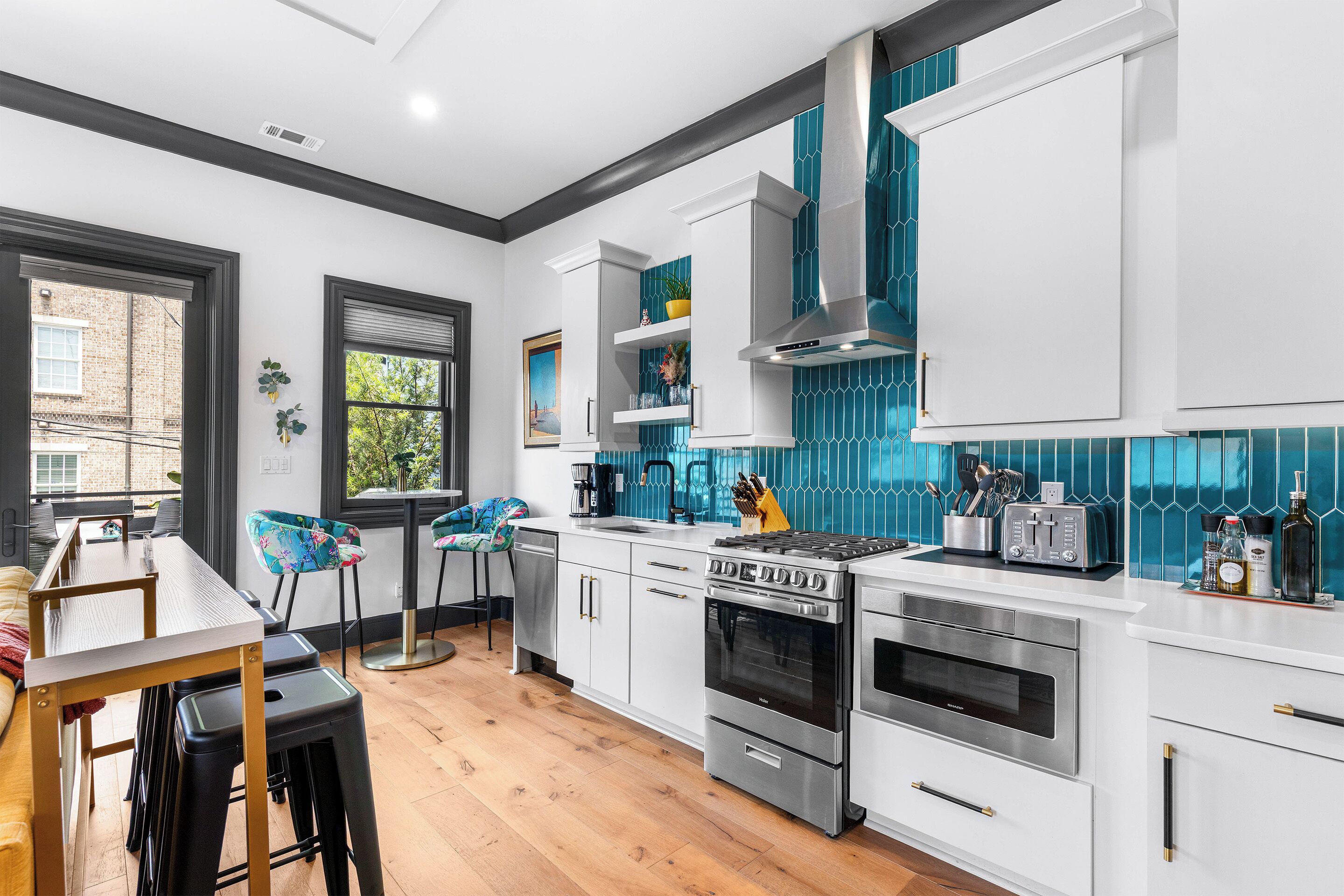 A modern kitchen with white cabinetry, stainless steel appliances, and a blue-tiled backsplash.