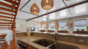 Een moderne keuken met een dubbele spoelbak, houten kastjes en hanglampen.