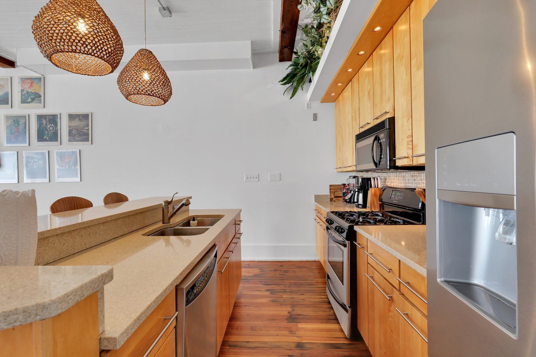Une cuisine moderne avec des meubles en bois, des appareils électroménagers en acier inoxydable et des luminaires suspendus.