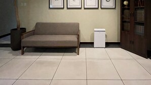 Un área de espera con un sofá, una mesita, una planta en maceta y cuadros en la pared.