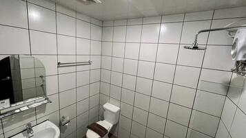 A small, tiled bathroom with a toilet, sink, and shower.