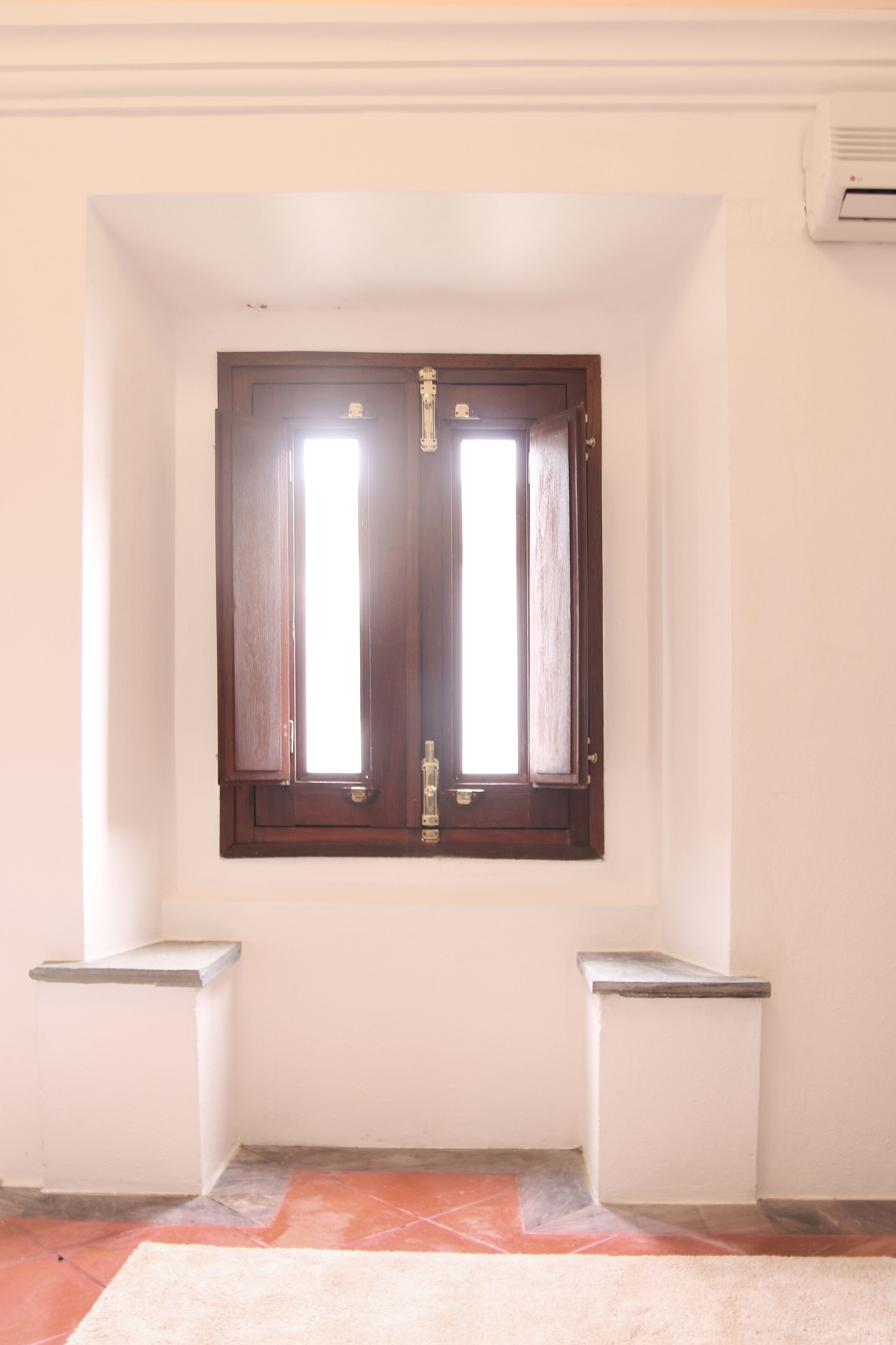 Um corredor com uma porta dupla, uma pequena lixeira em cada lado e piso revestido de azulejos.