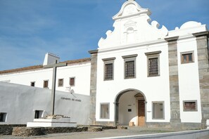 A white building with a stone facade, an arched entrance, and a bell tower. - Convento da Orada (Reguengos de Monsaraz)