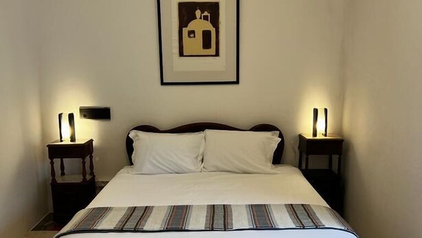 A bedroom with a large bed, two bedside tables with lamps, a framed picture on the wall, and a carpeted floor. - Convento da Orada (Reguengos de Monsaraz)