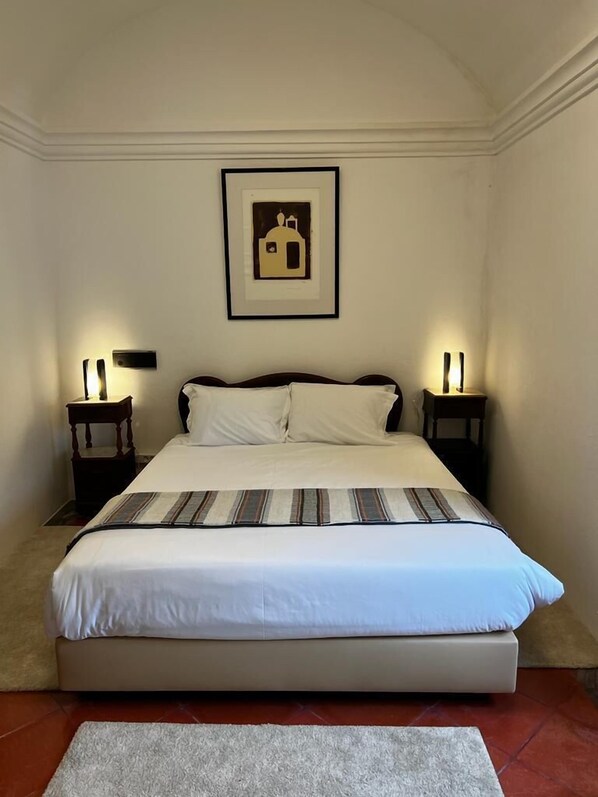 A bedroom with a large bed, two bedside tables with lamps, a framed picture on the wall, and a carpeted floor. - Convento da Orada (Reguengos de Monsaraz)