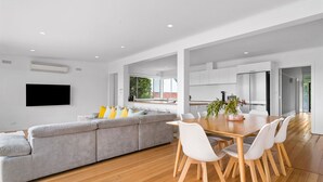 A modern kitchen with white cabinets, a wooden dining table, and a gray sofa. - Sorrento Family Fun House - Unbeatable Location (Sorrento)