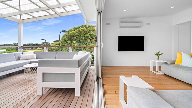 A modern living room with a large sofa, a coffee table, and a TV mounted on the wall. - Sorrento Family Fun House - Unbeatable Location (Sorrento)