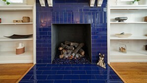 A fireplace with blue tiles, a white mantel, and a small figurine on the floor. - Splendor on the Lake, 1928 Cottage-Walk Everywhere (Saint Augustine)
