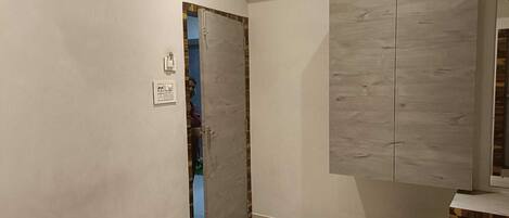 Un dormitorio con una cama, un armario, un cubo de basura y una toma de corriente.