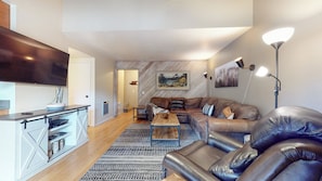Un salon moderne avec un canapé, une table basse et un téléviseur à écran plat.