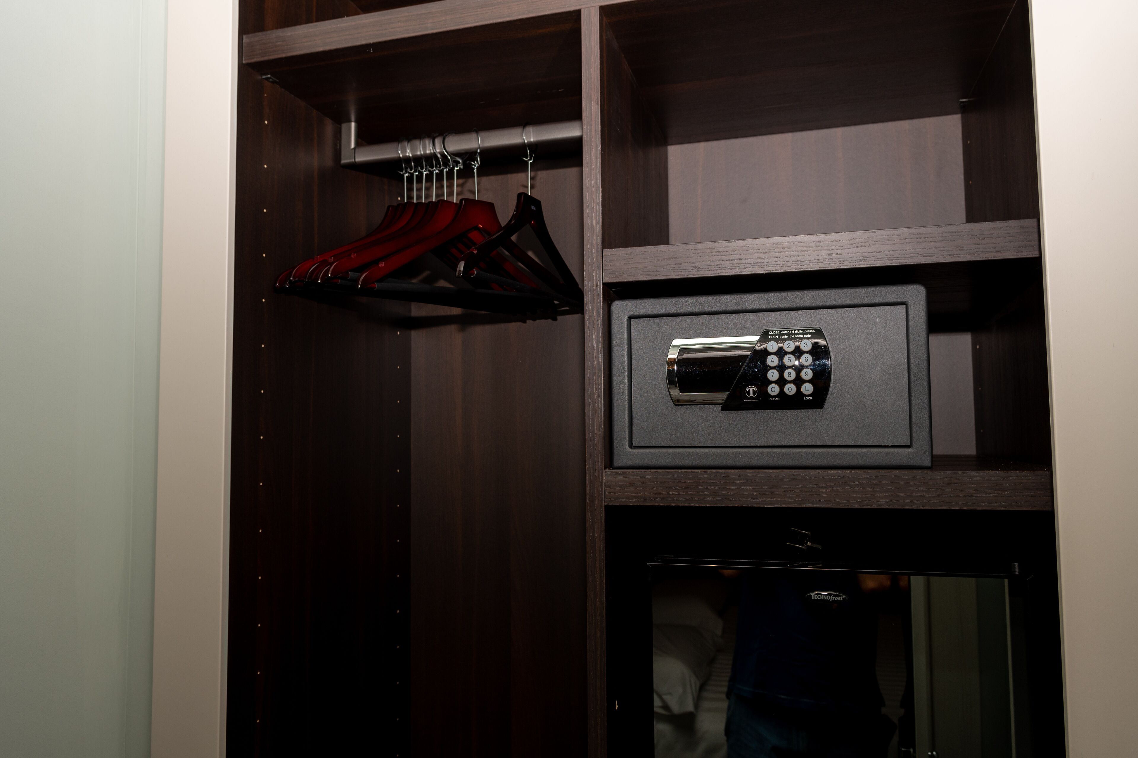A closet with hanging clothes and a safe.