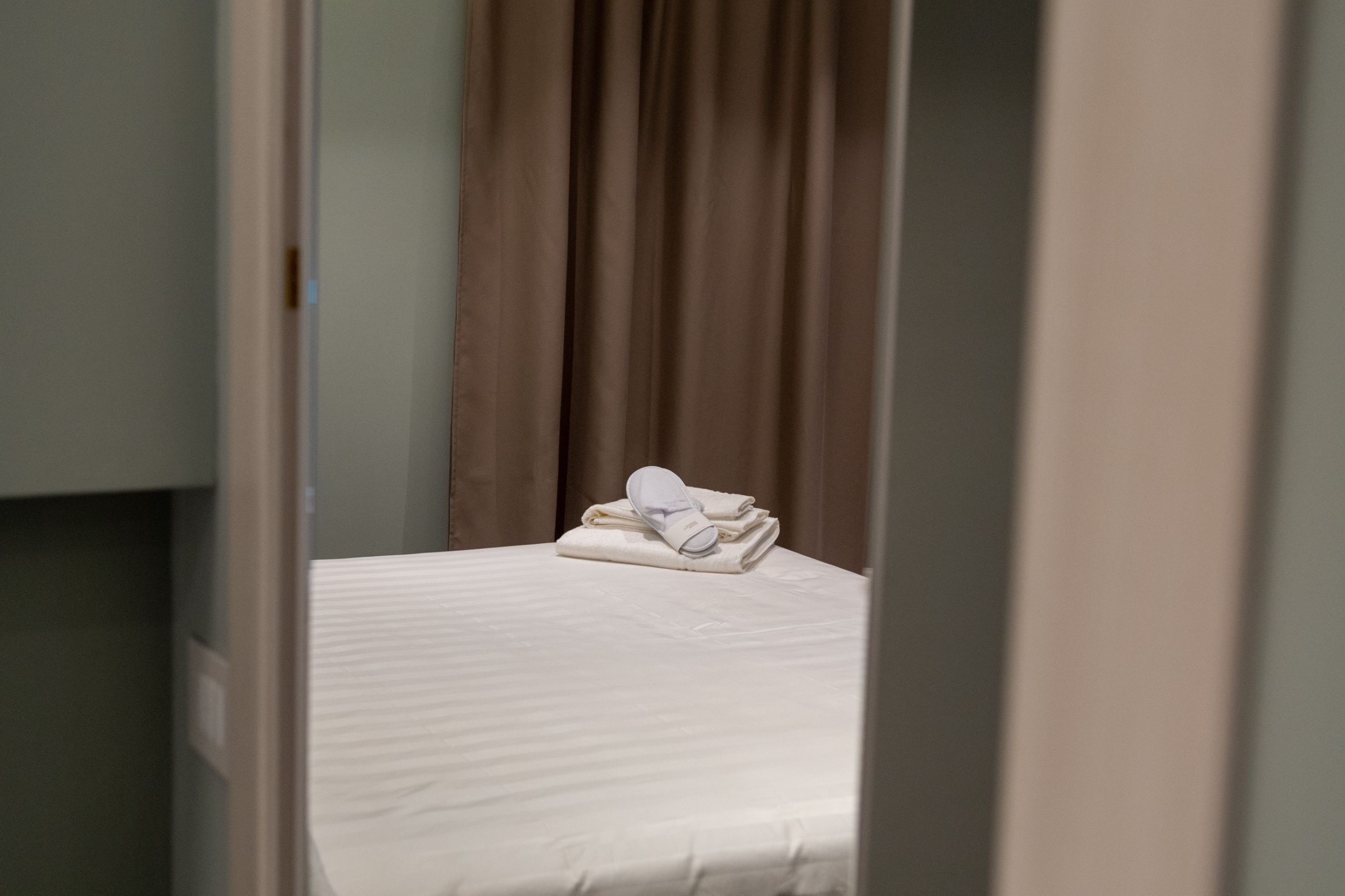 Une chambre d’hôtel avec un lit bien fait, un ensemble de serviettes et un rideau.