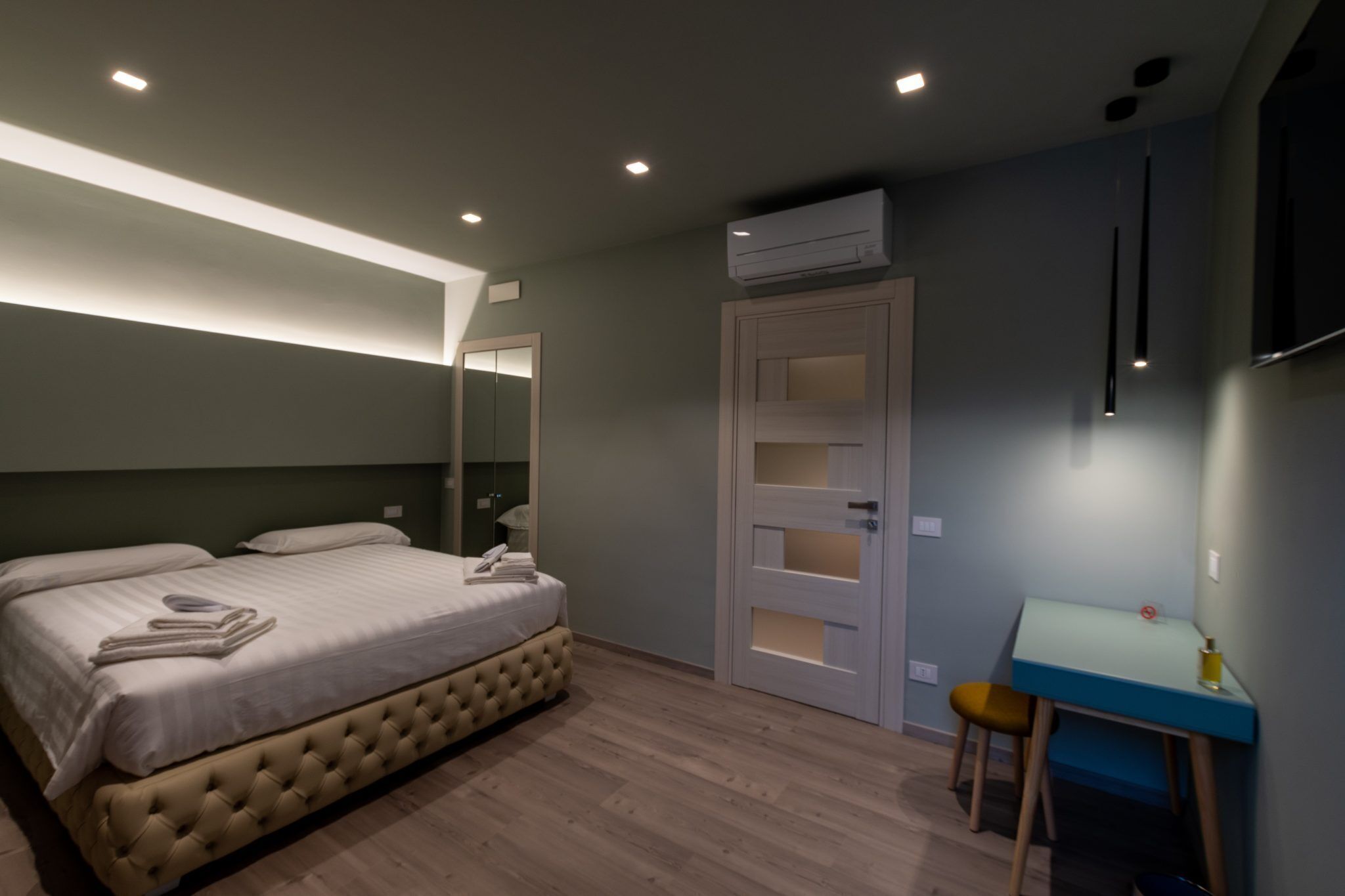 A bedroom with a bed, a desk, and a wardrobe.
