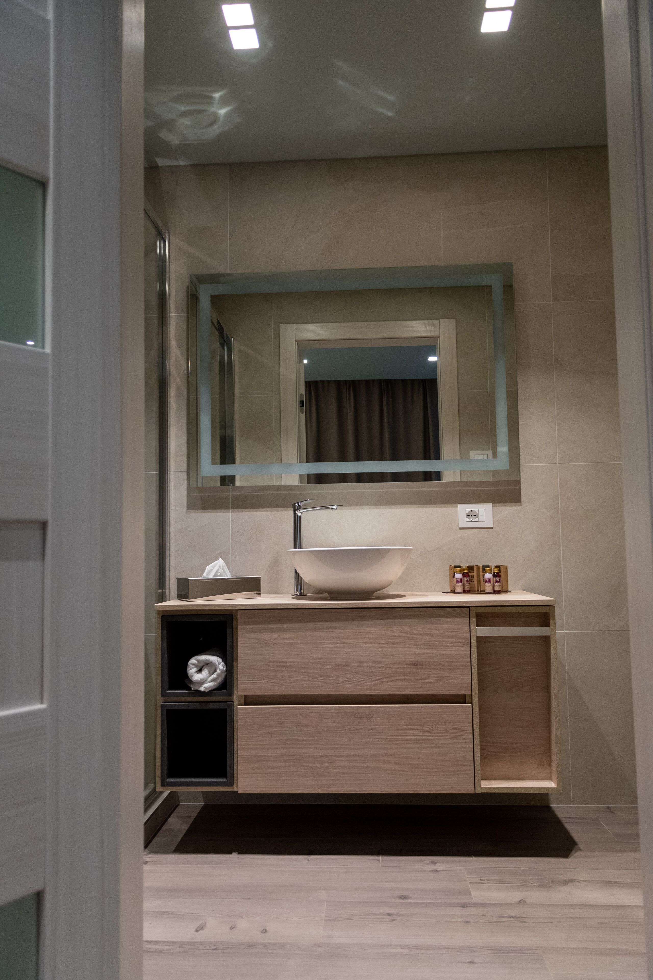 Un bagno moderno con uno specchio grande, un lavandino e un mobile contenitore con cassetti.