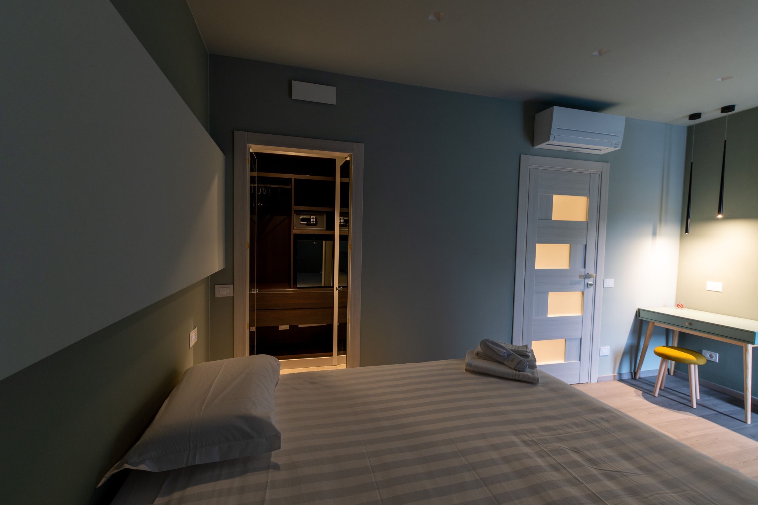 A bedroom with a bed, a desk, and a wardrobe.