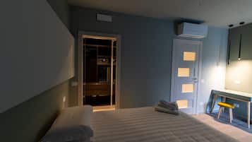 A bedroom with a bed, a desk, and a wardrobe.