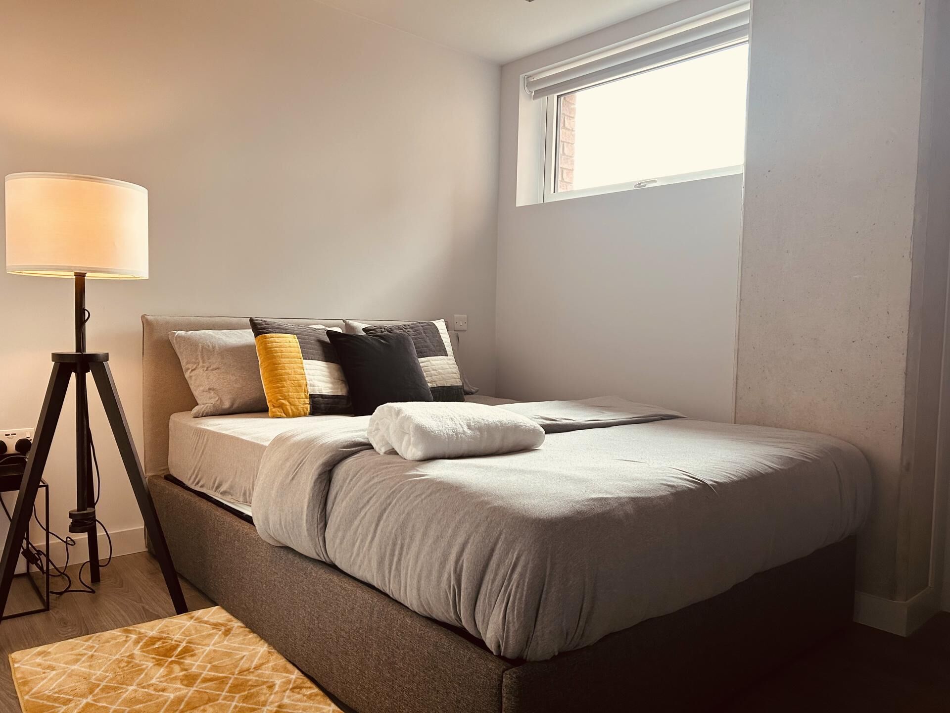 Une chambre à coucher bien rangée, avec un lit, une lampe de chevet et une fenêtre.