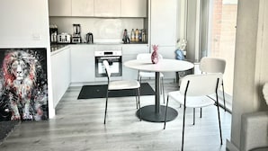 A modern kitchen with white cabinets, a round dining table, and a large window. - Captivating 2-bed Skyview Apartment in Leeds (Leeds)