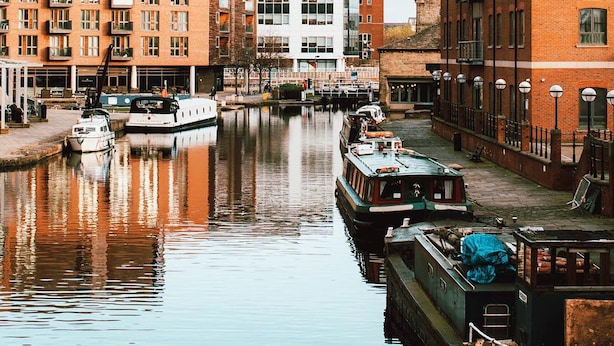 A canal with boats docked, surrounded by buildings with balconies and windows. - Captivating 2-bed Skyview Apartment in Leeds (Leeds)