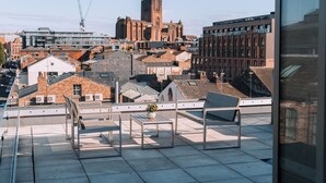 A rooftop terrace with a table and chairs, offering a view of a historic church and modern buildings. - Ropewalks Hotel (Liverpool)