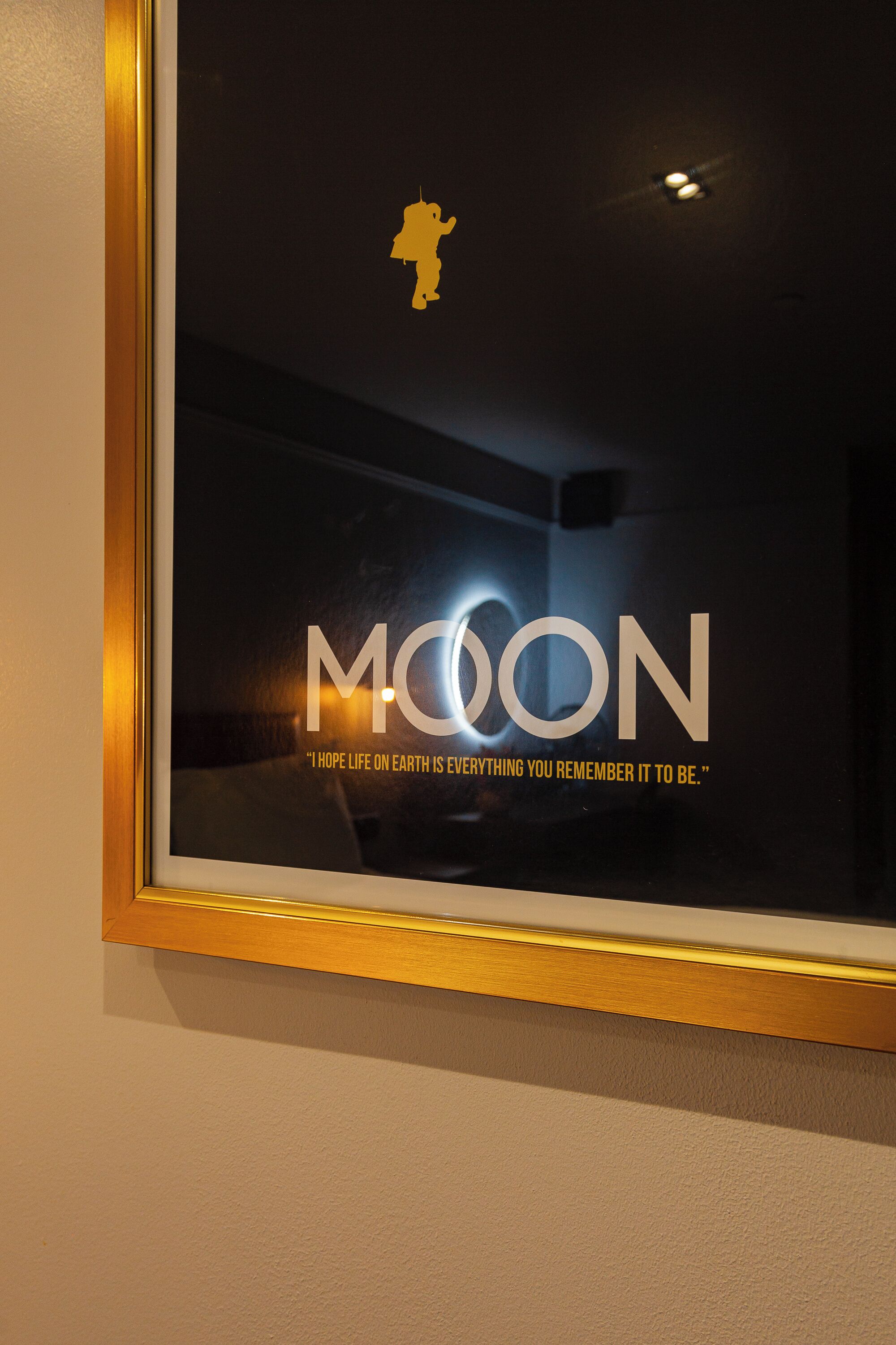 Une citation encadrée est accrochée au mur, avec le mot « LUNE » et la silhouette d’une personne en train d’escalader une montagne.