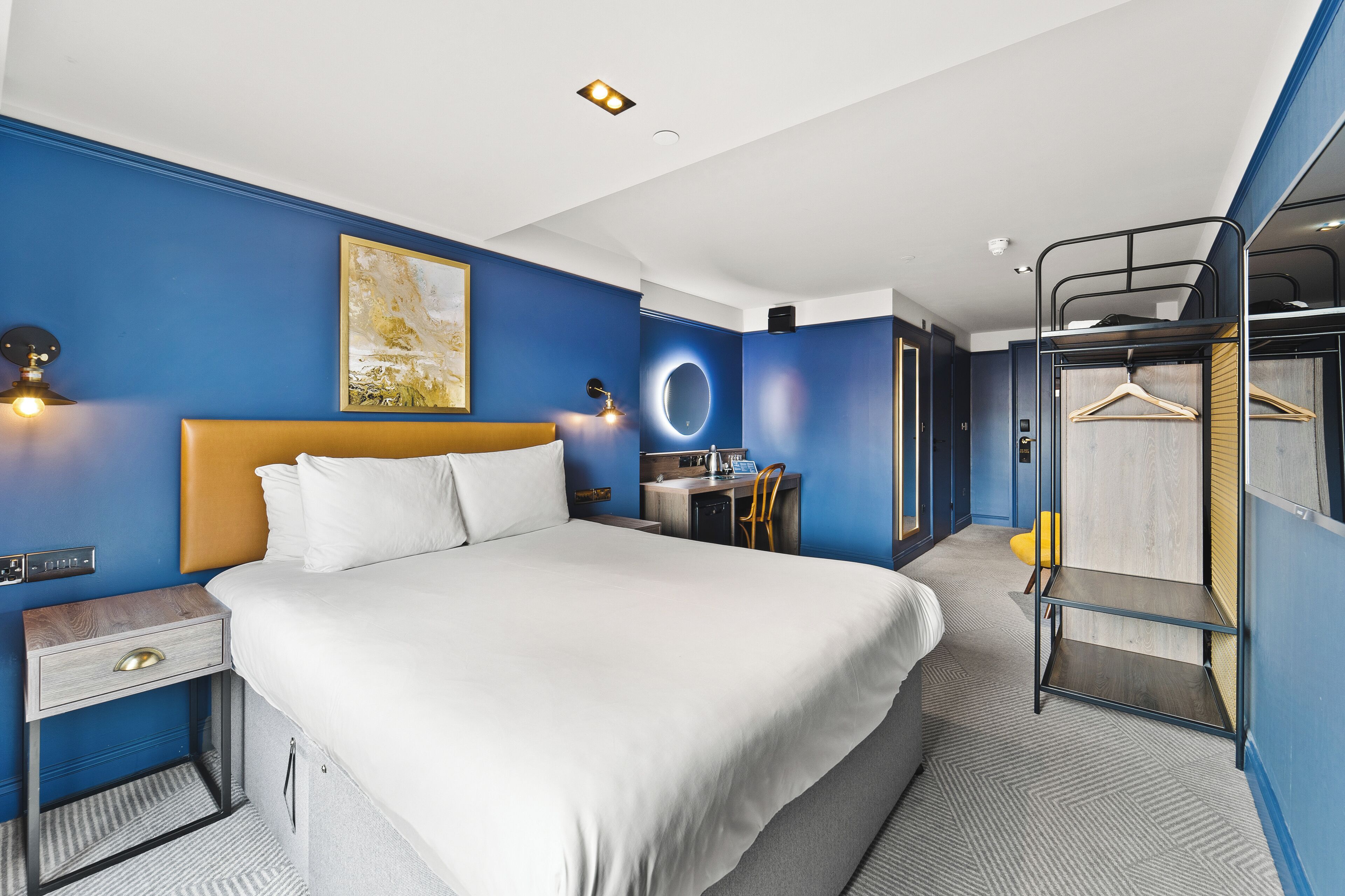 Una habitación de hotel con una cama grande, un escritorio, una silla, un armario y una litera.
