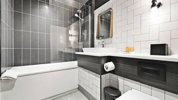 A modern bathroom with a glass-enclosed shower, a white bathtub, and a vanity with a mirror.