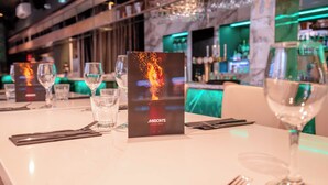 A restaurant setting with a table set for dining, a bar area in the background, and a menu stand with a fiery design. - Ropewalks Hotel (Liverpool)