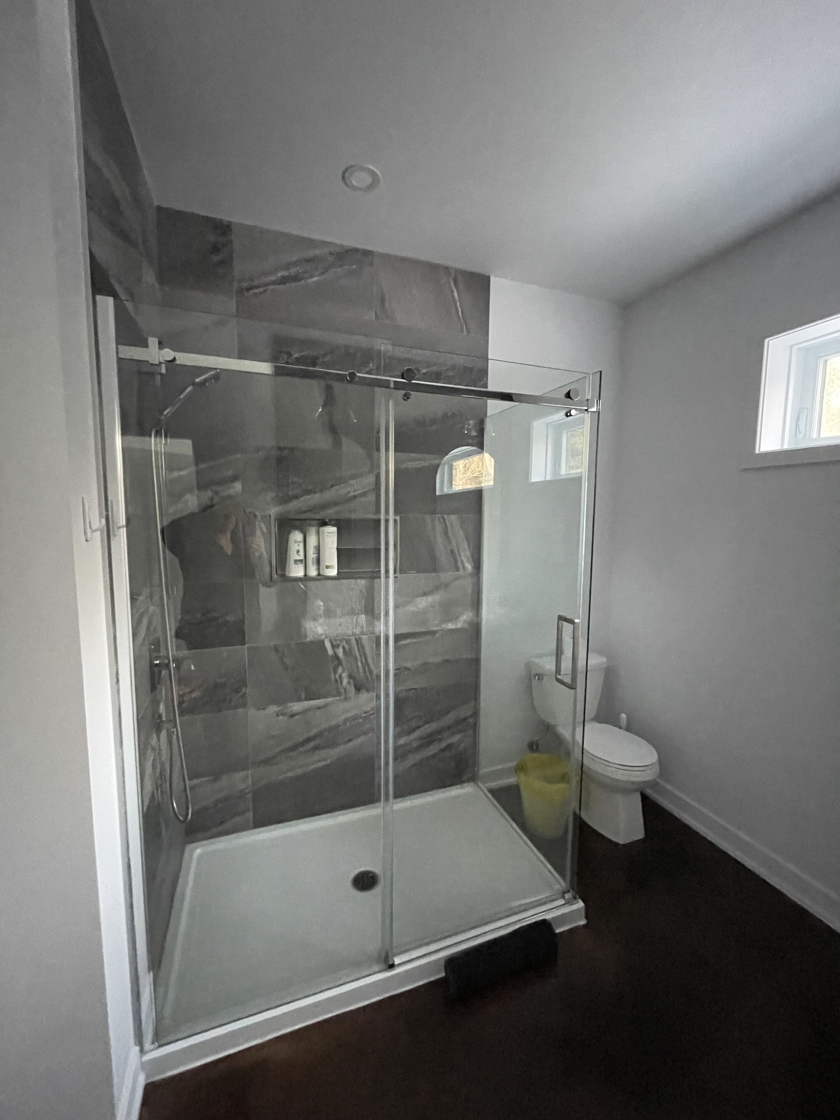 Et moderne badeværelse med bruseniche, toilet og marmorbeklædt væg.