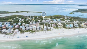 An aerial view of a coastal residential area with houses, a beach, and a clear sky. - Bayfront Cottage with Screened Porch (Port St Joe)