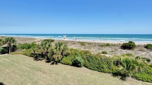 Eine Küstenlandschaft mit Strand, einem weißen Gebäude und dichter Vegetation.
