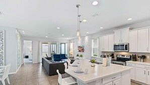 Een moderne keuken met witte kastjes, een centraal eiland en een eethoek met een blauwe bank.