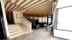 Um hall amplo com escada, balcão de recepção e área de estar.